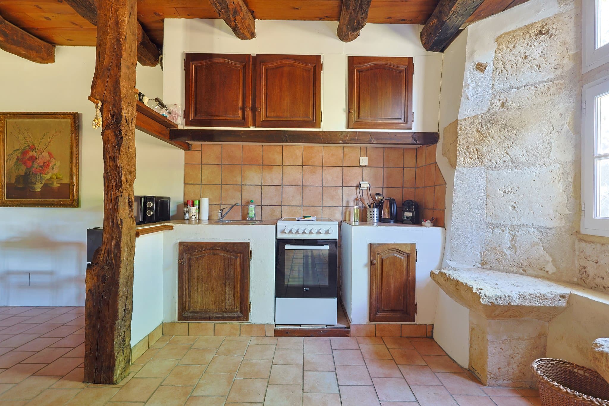 The open kitchen at Andrea's House, between exposed beams and stonework.