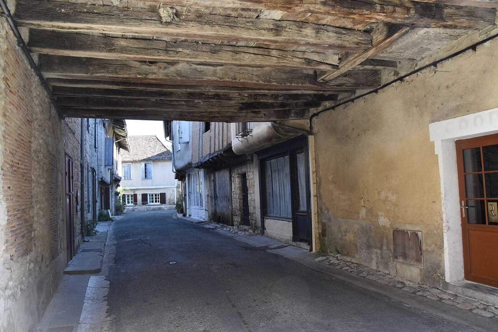 A street in Issigeac running under an old house through a covered passage.