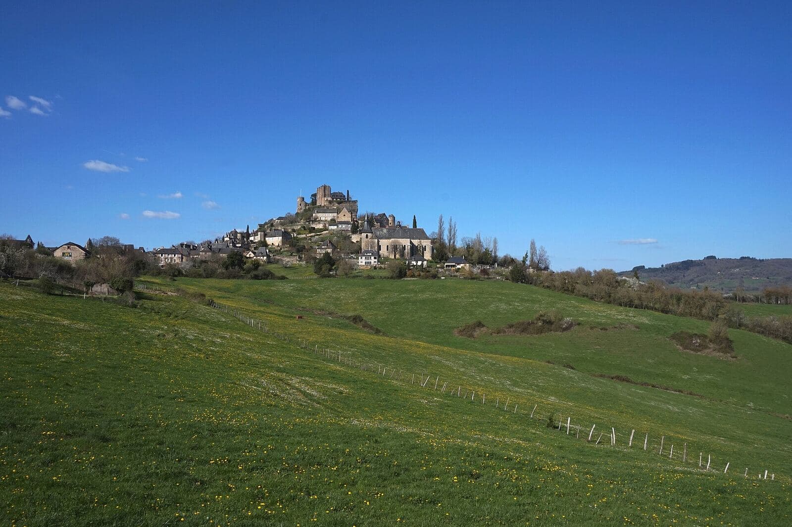 Turenne on its hill above the meadows: the village and the château's tower.