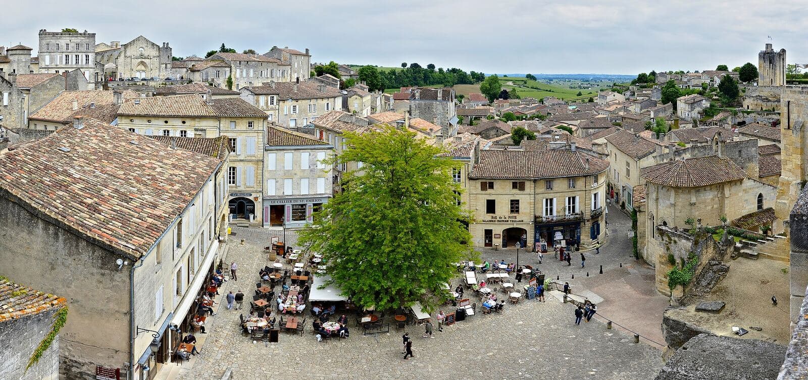 Saint-Émilion from above: the town's rooftops and the square lined with café terraces.