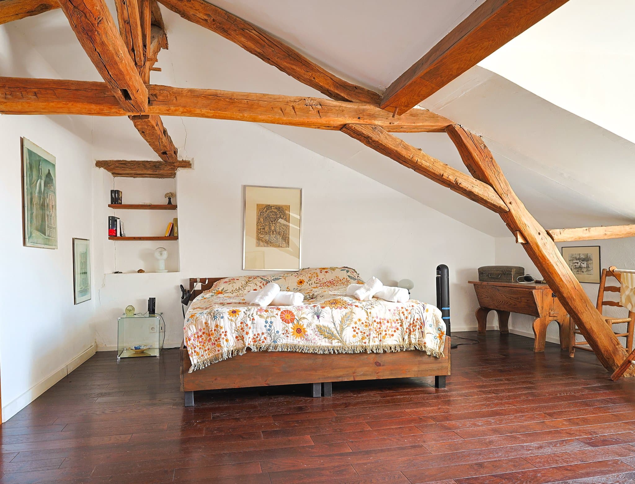 A first-floor bedroom at Chez Momône, beneath the exposed roof beams.