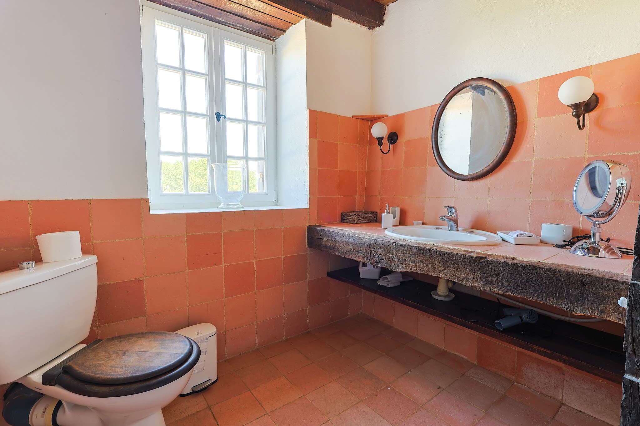 The pink ground-floor bathroom at Chez Momône, with its stone basin and terracotta tiles.