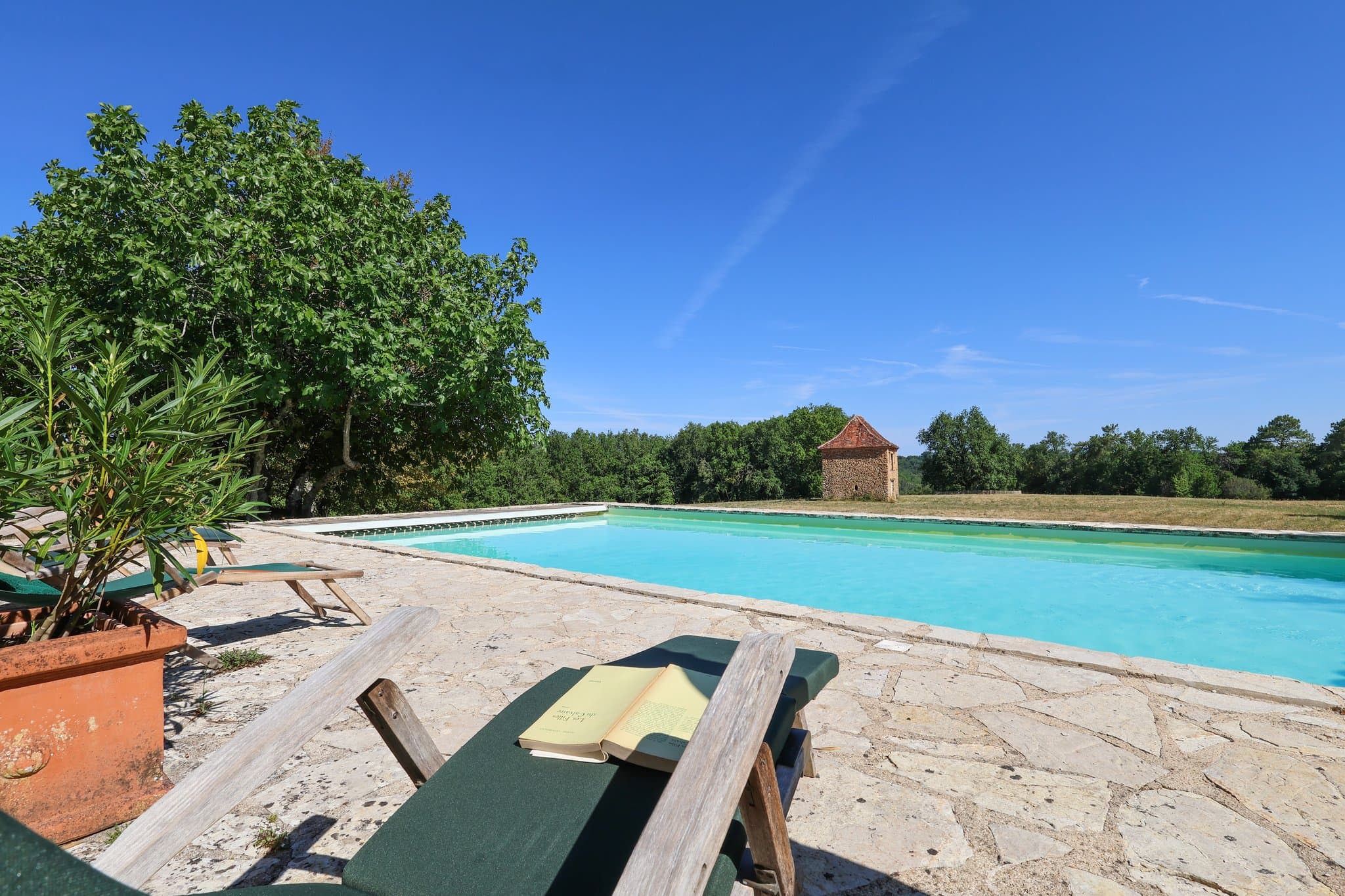 An open book on a sun lounger by the pool, at the end of a summer day.