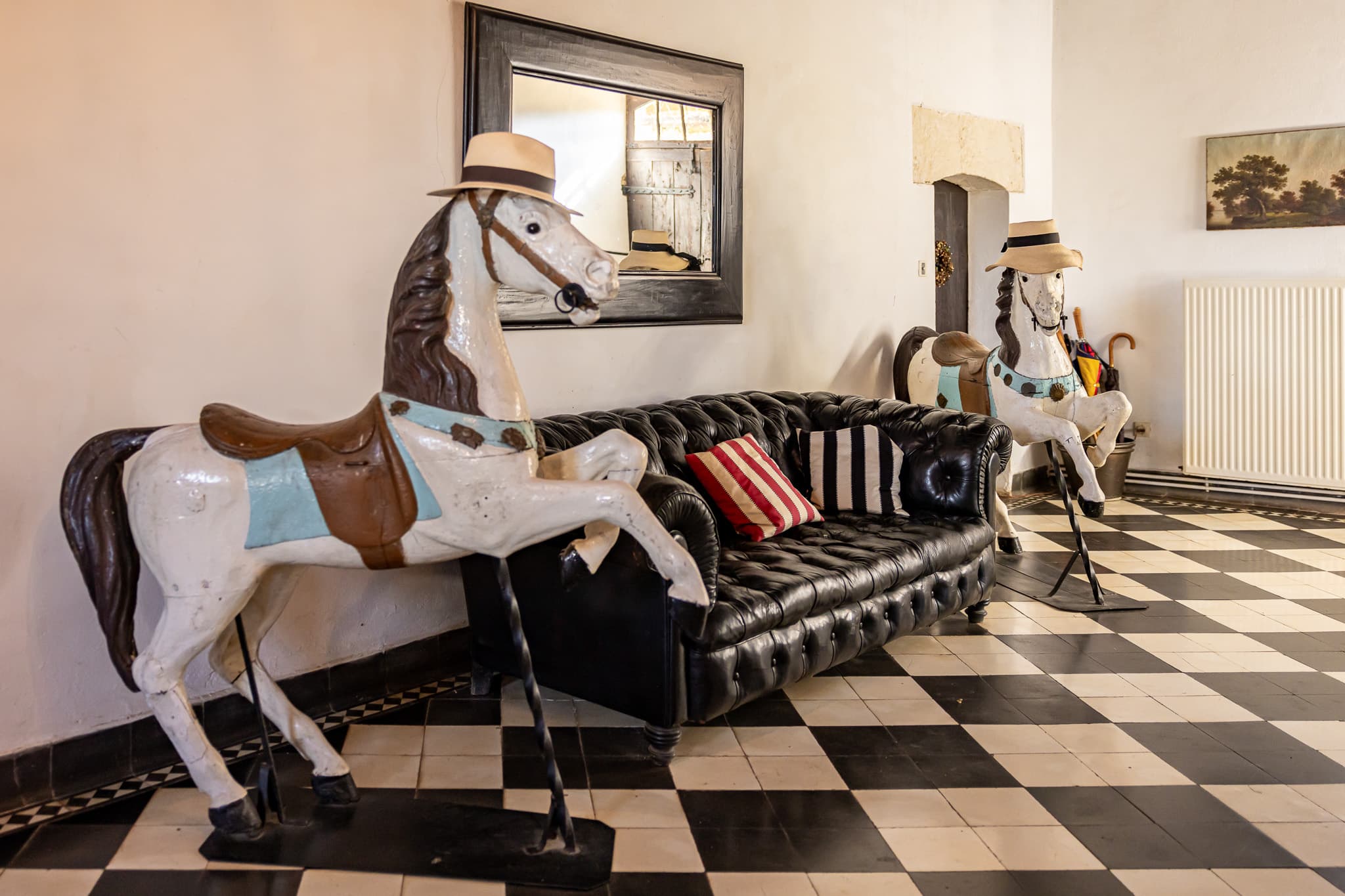 The main house's entrance hall, with its antique carousel horses and leather Chesterfield sofa.